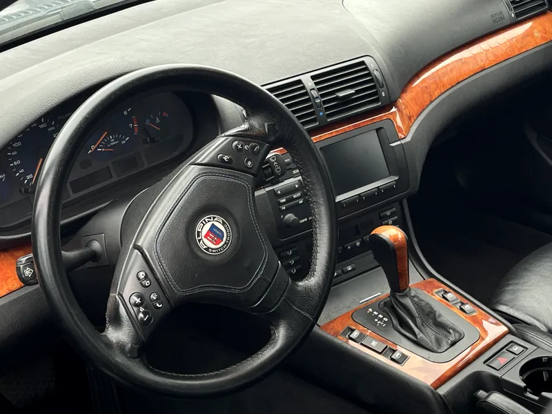 Klasikinio BMW Alpina salonas su odiniu vairu, analoginiais prietaisais ir medžio apdaila