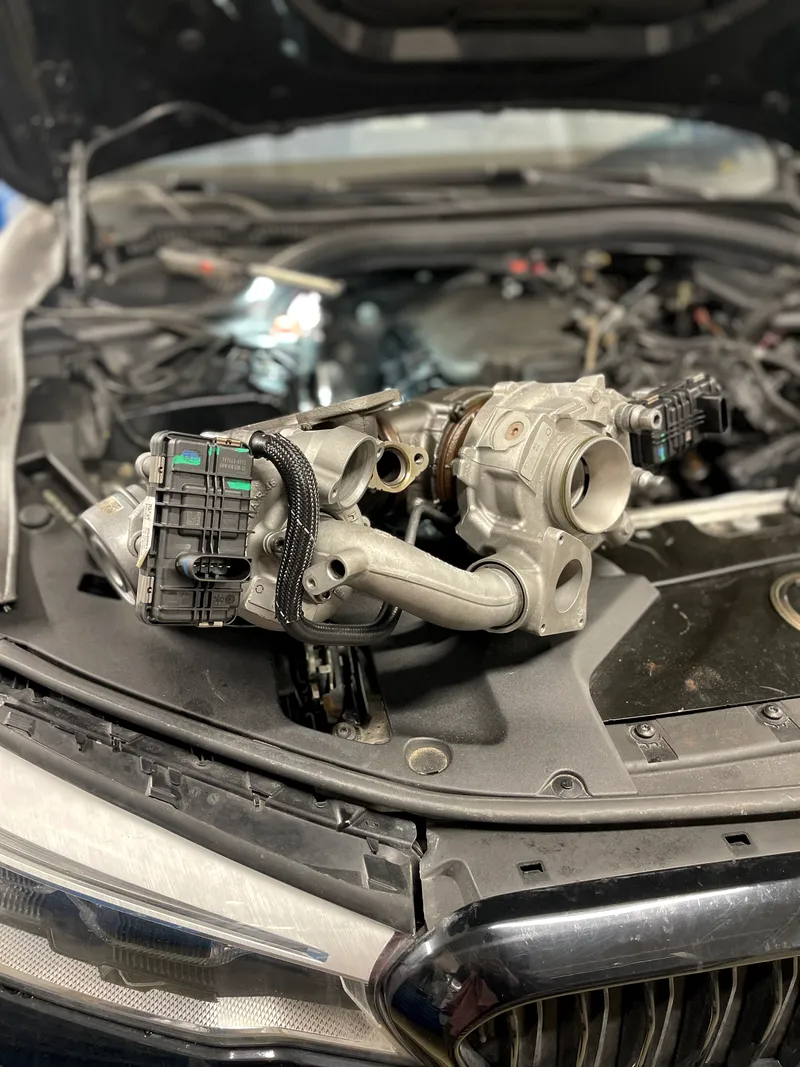 Nuimta turbina su valdymo pavara, padėta ant atidaryto BMW variklio skyriaus