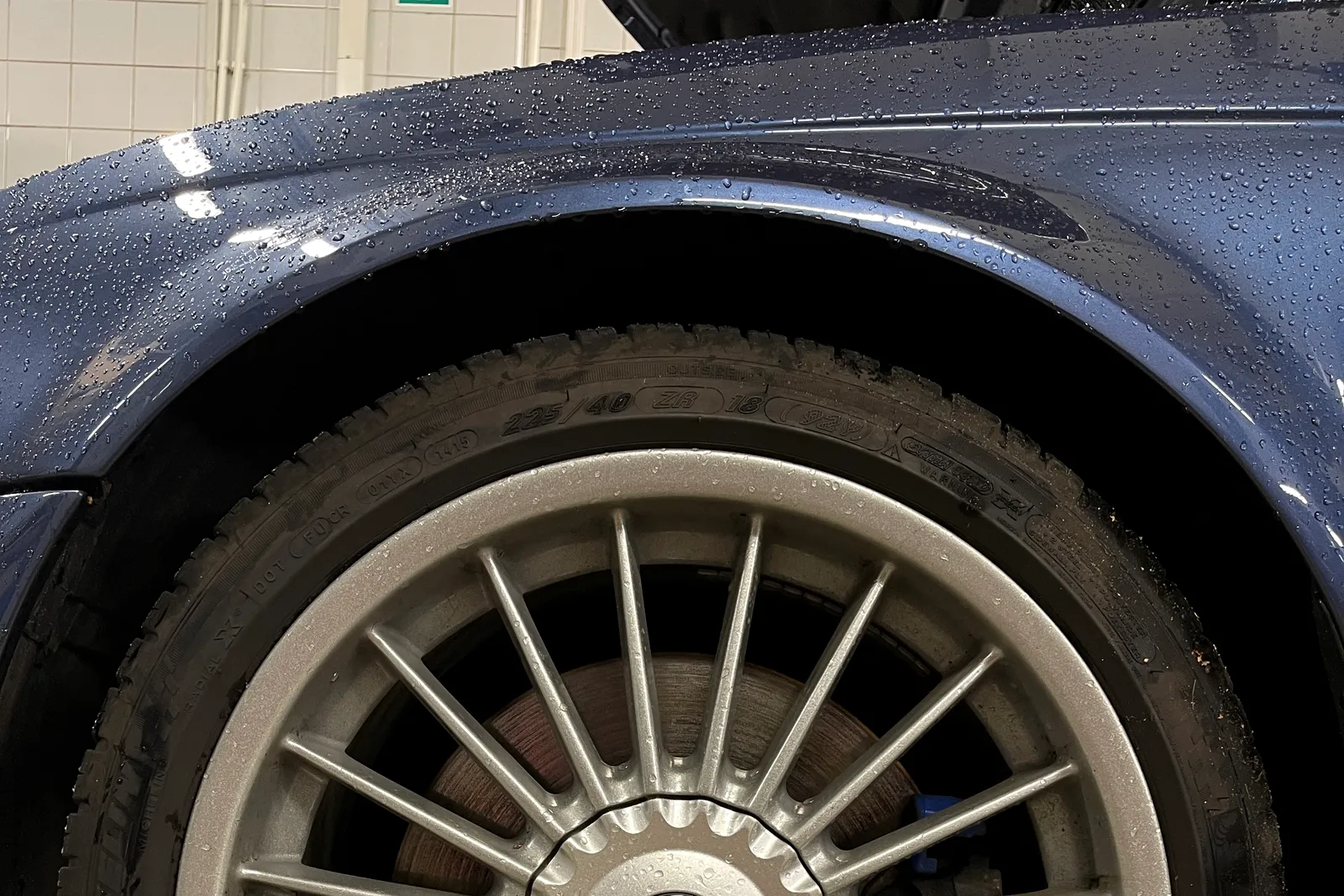 Ratlankis ir padanga ant ką tik nuplauto BMW serviso patalpoje, pro stipinus matomas stabdžių diskas